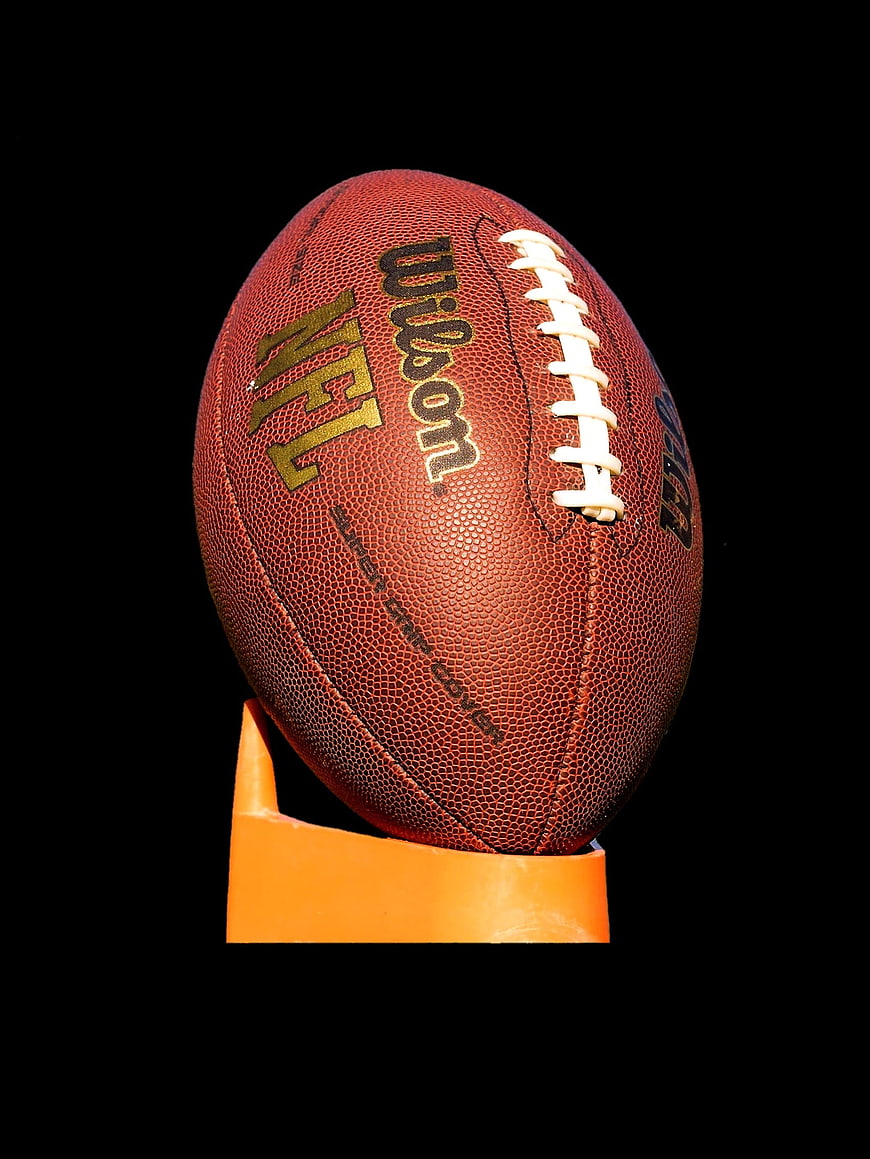 NFL Wilson American Football on Orange Stand Against Black Background