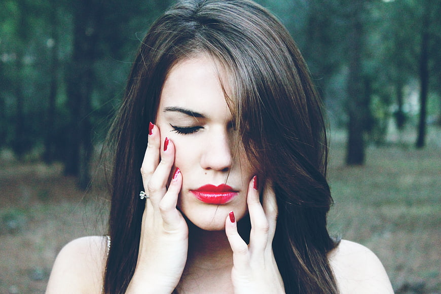 Close-up portrait of woman with red lipstick in forest