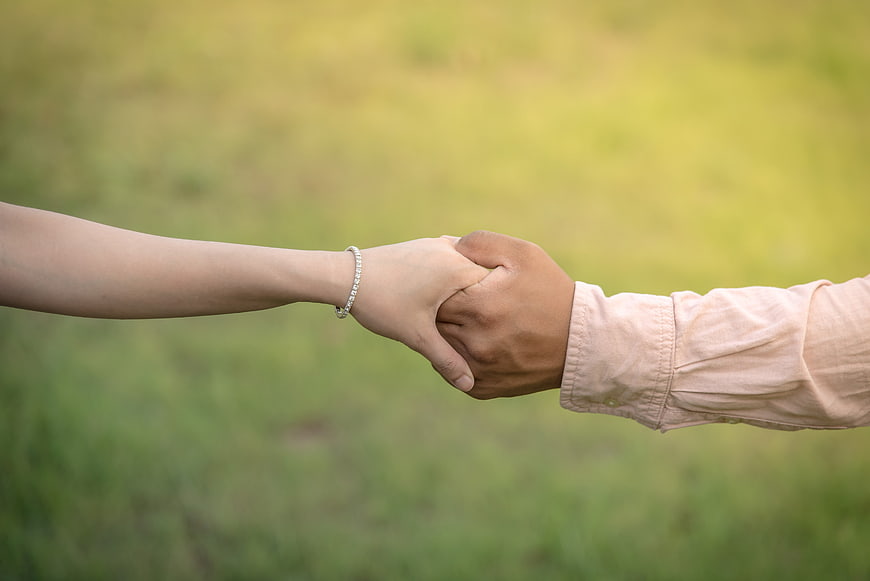 Couple Holding Hands in Green Field