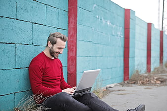 Happy Man Using Laptop Against Colorful Wall