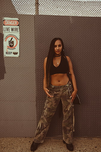Woman in Camo Pants and Black Crop Top Against Metal Wall