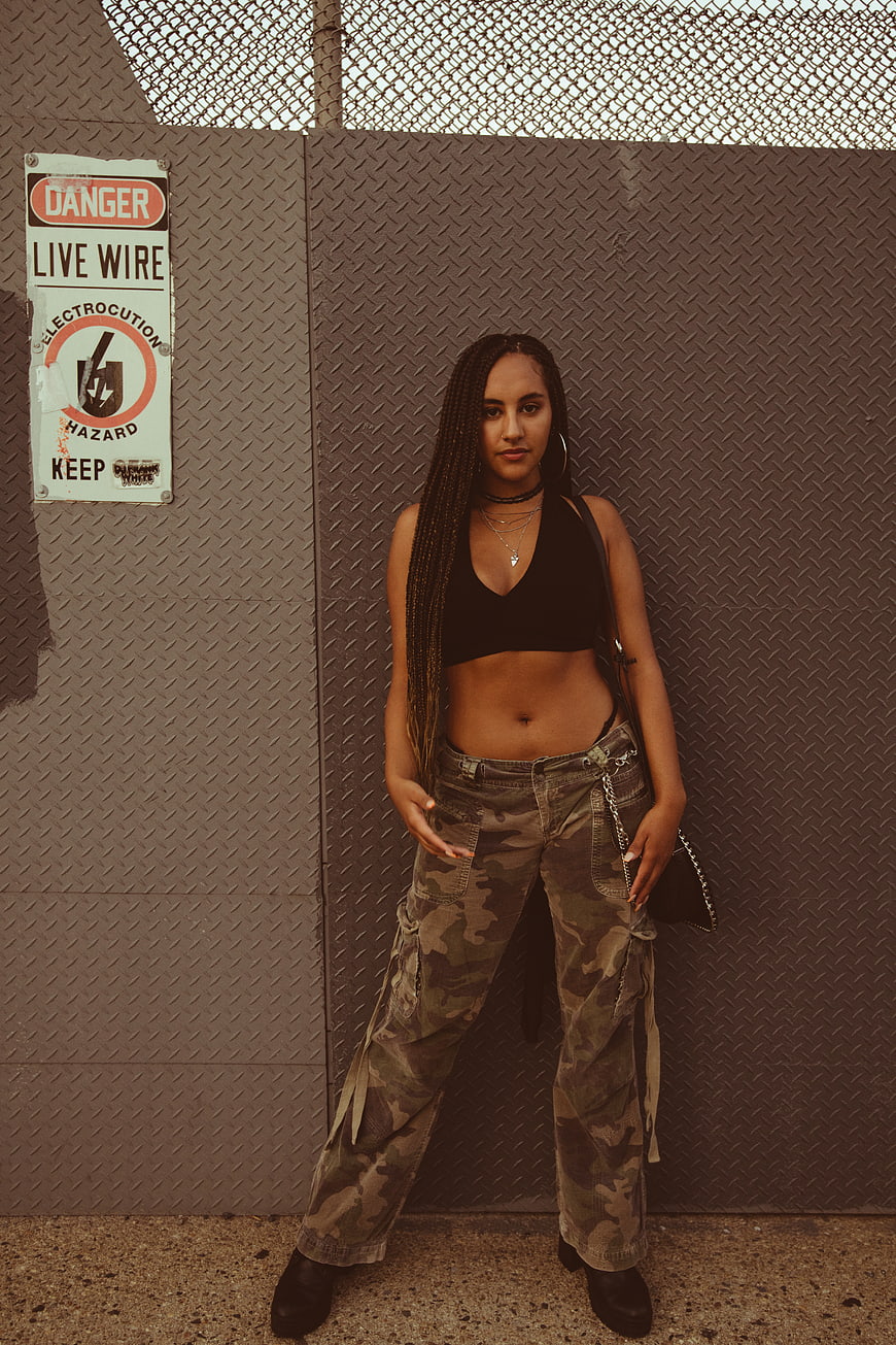 Woman in Camo Pants and Black Crop Top Against Metal Wall