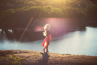 Woman in Pink Dress Standing by Lake at Sunset