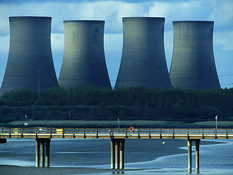 Four massive cooling towers of a power plant behind a bridge