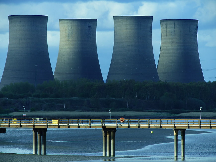 Four massive cooling towers of a power plant behind a bridge