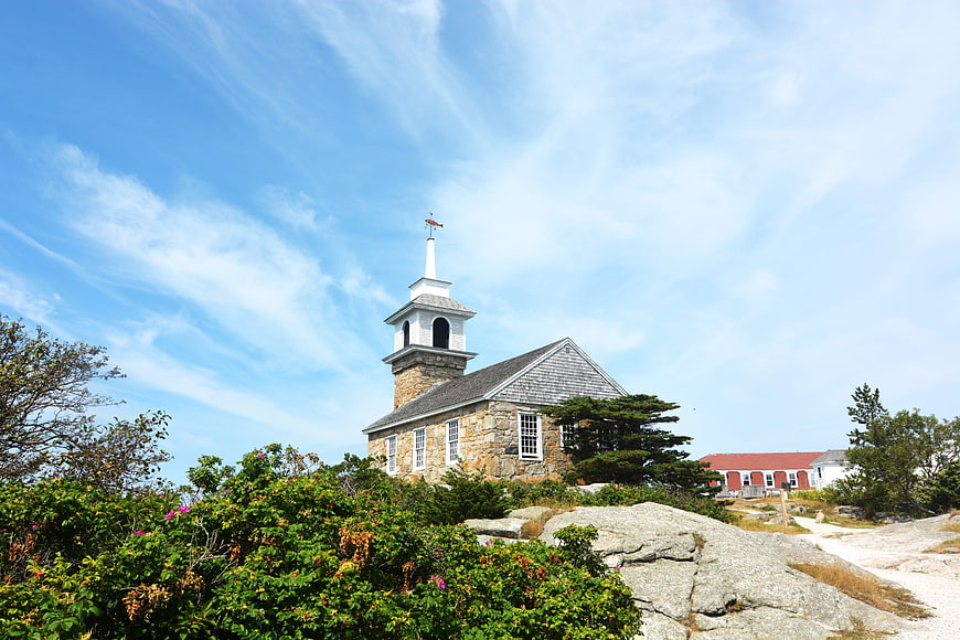 Stone church with white steeple on rocky hillside