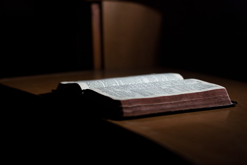 Open Bible on Wooden Table in Dim Light