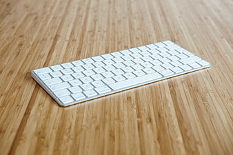 White Wireless Keyboard on Wooden Desk Surface