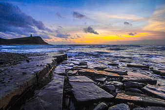 Dramatic Sunset Over Jurassic Coast Rocks and Ocean Waves