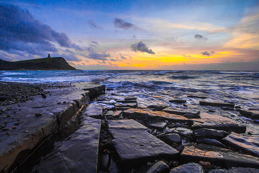 Dramatic Sunset Over Jurassic Coast Rocks and Ocean Waves