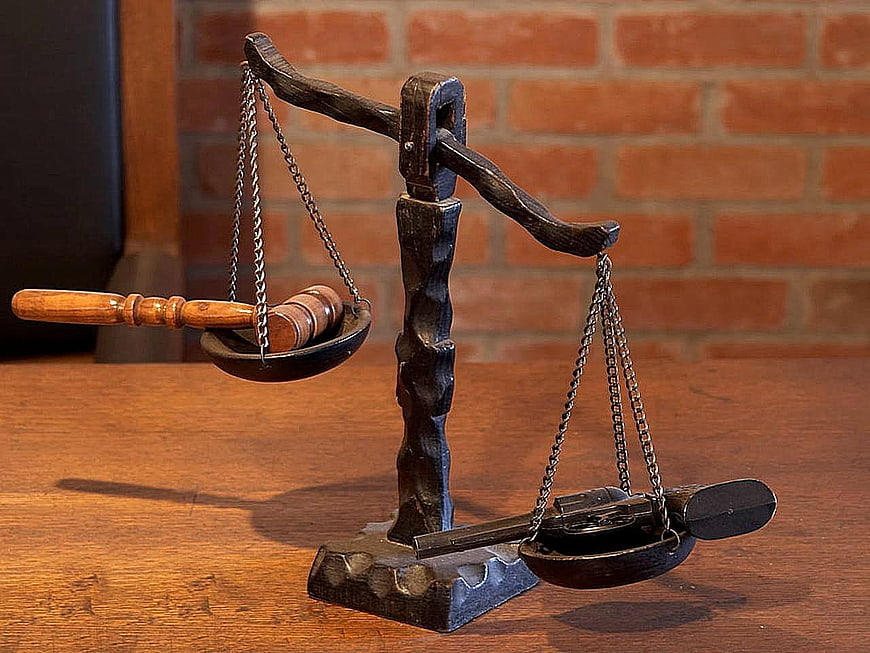 Wooden Scales of Justice with Gavel and Handcuffs on Brick Background