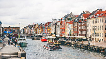 Colorful historic buildings along a canal with boats and tourists
