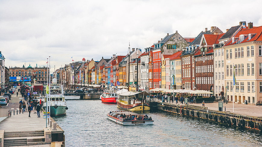 Colorful historic buildings along a canal with boats and tourists