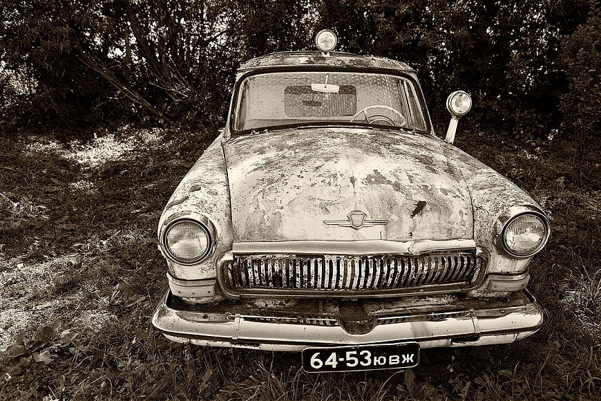 Front view of abandoned vintage Soviet car in forest