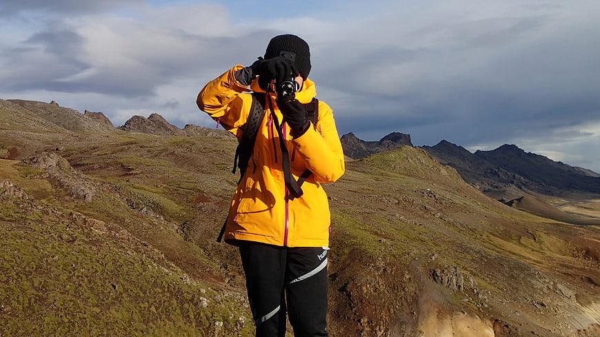 Photographer in Yellow Jacket Taking Photo in Mountains