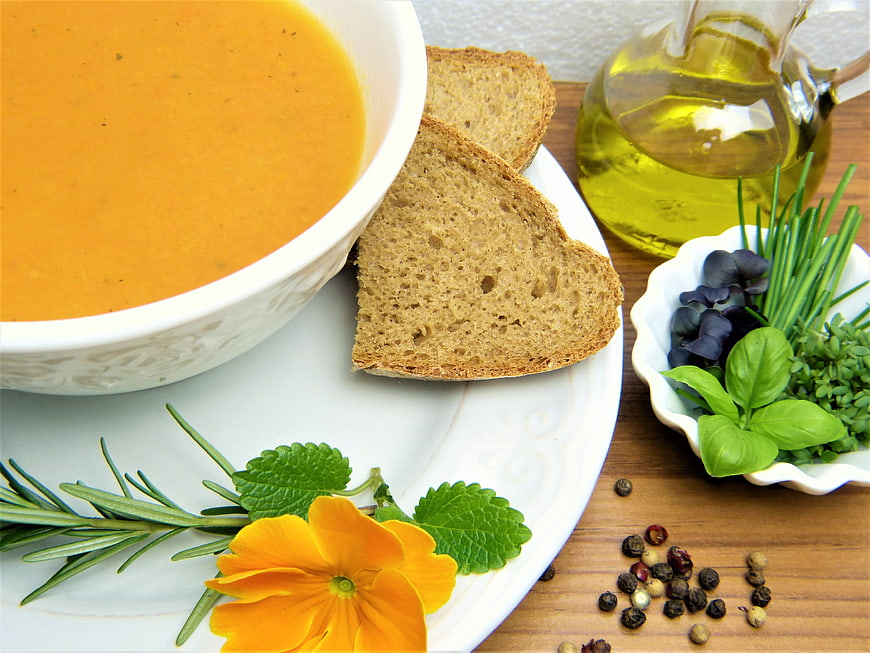 Creamy carrot soup with bread and fresh herbs