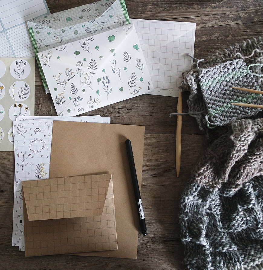 Knitting project with stationery on wooden table