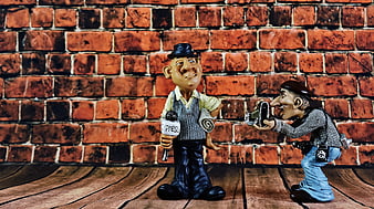 Cute ceramic figurines of a journalist and photographer against a brick wall