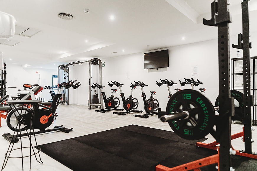 Modern empty gym interior with exercise bikes and weight rack