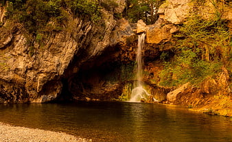Serene waterfall cascading into a calm river pool surrounded by rocky cliffs