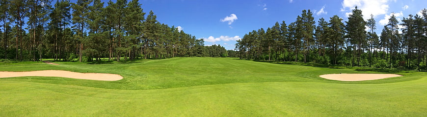 Panoramic view of a lush green golf course fairway with sand traps