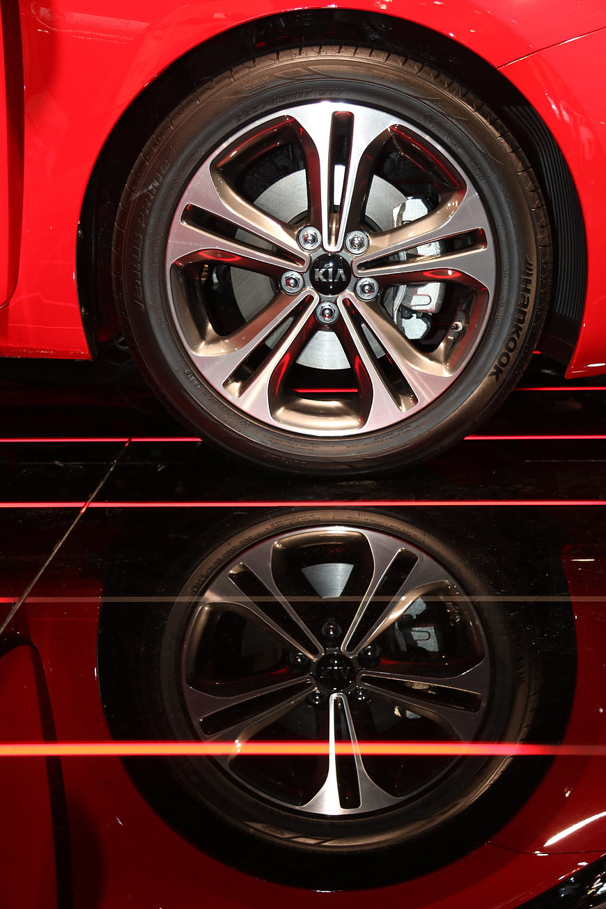 Close-up of red Kia car wheel with reflection on glossy floor