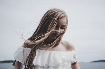 Blonde Woman with Windblown Hair in White Off-Shoulder Top
