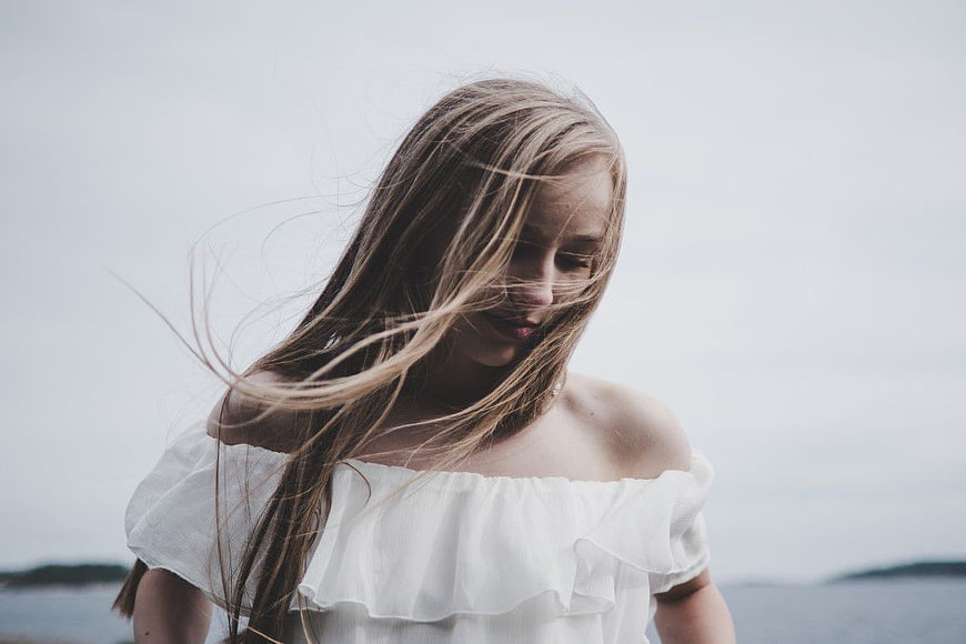 Blonde Woman with Windblown Hair in White Off-Shoulder Top