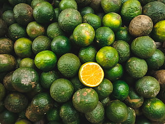 Top view of green oranges with one sliced orange