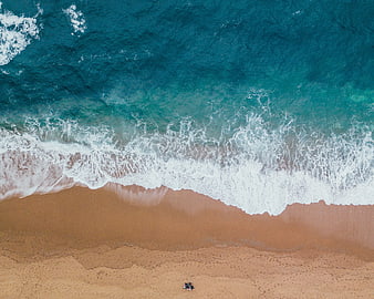 Aerial view of turquoise ocean waves crashing on sandy beach