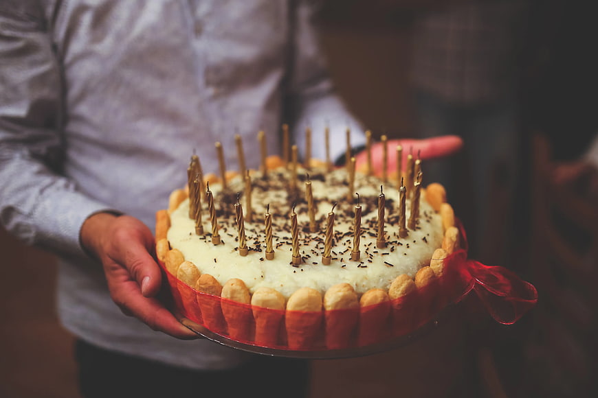 Man holding traditional birthday cake with candles