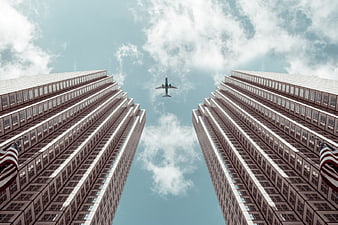 Worm's eye view of airplane flying between skyscrapers