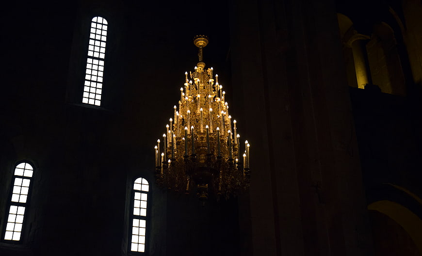 Ornate Golden Chandelier in Dark Cathedral Interior