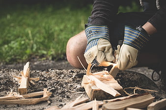 Person Starting Fire With Ferro Rod And Feather Sticks Outdoors