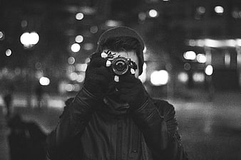 Man with camera taking photo at night in city