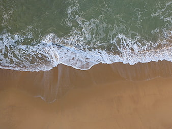 Aerial View of Ocean Waves Meeting Sandy Beach Shoreline