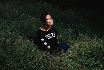 Happy woman with short hair sitting in tall grass