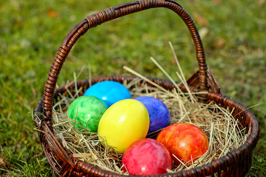 Colorful Easter Eggs in Wicker Basket on Grass