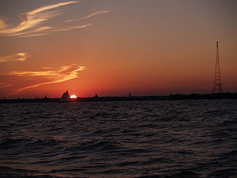 Silhouette of Sailboat on Ocean at Sunset with City Skyline