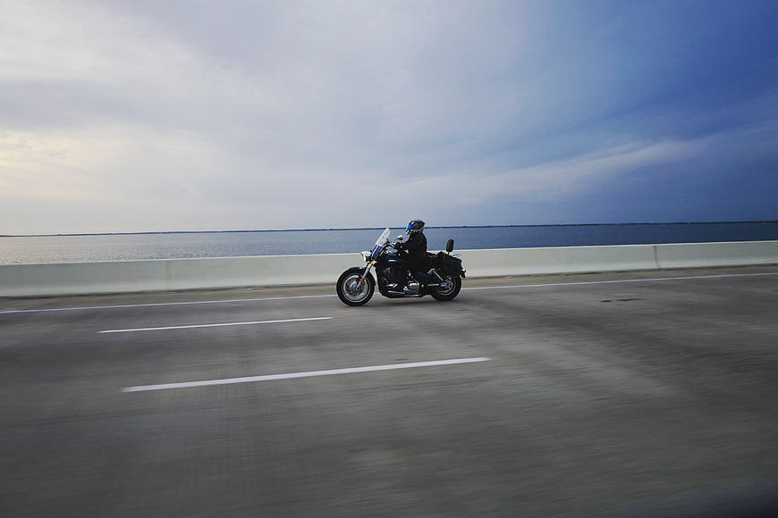 Motorcyclist riding on coastal highway bridge