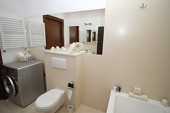 Modern beige bathroom interior with washing machine and bathtub