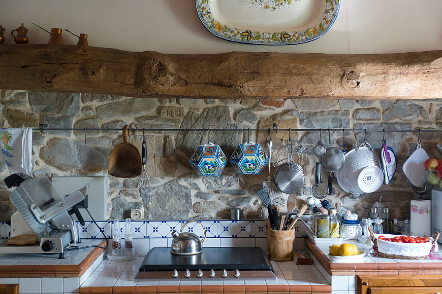 Rustic Tuscan Farmhouse Kitchen Interior With Stone Wall And Hanging Utensils