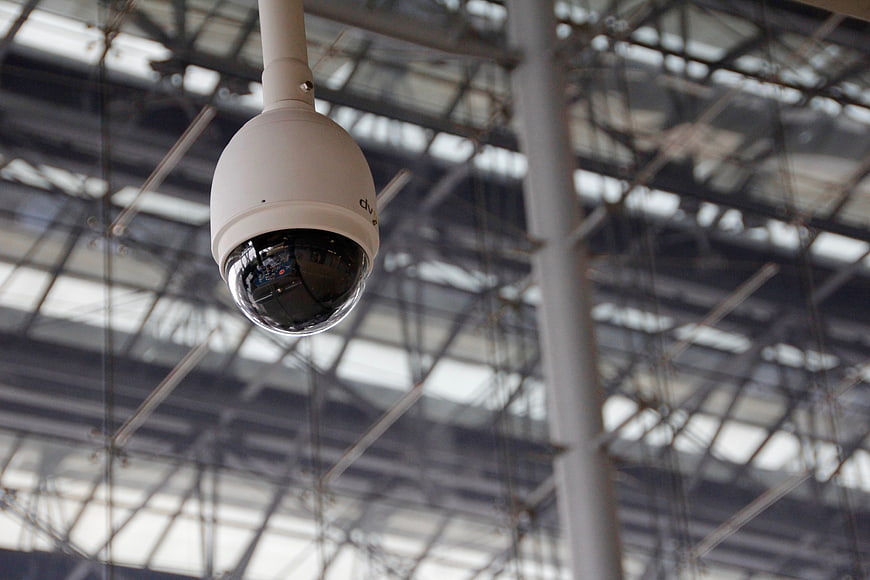 White Dome Security Camera Hanging from Industrial Ceiling