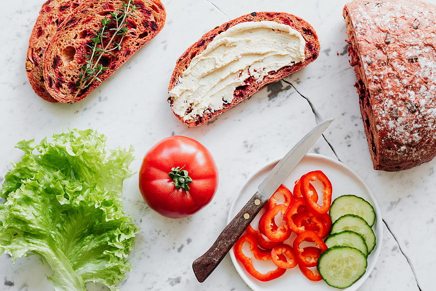 Flat lay of cranberry bread, hummus, and fresh vegetables