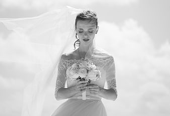 Bride with flowing veil holding bouquet in black and white