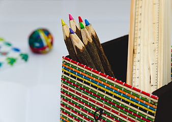 Colorful pencils in woven basket with wooden ruler