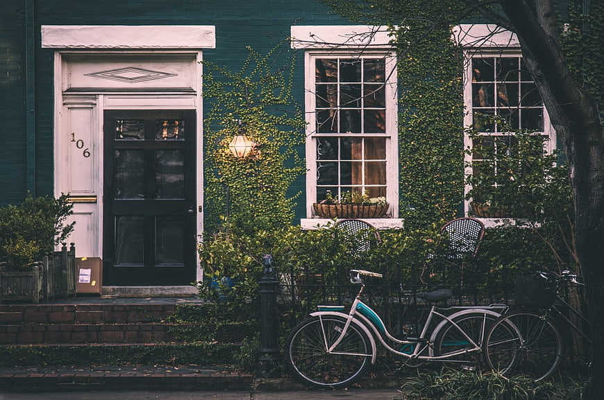 Vintage Bicycle Parked in Front of Green House with Ivy