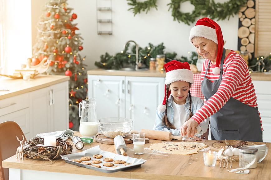 Grandmother and granddaughter baking Christmas cookies in festive kitchen
