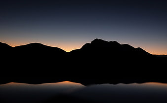 Silhouette of Mountains Reflected in Calm Water at Dusk