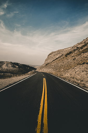 Empty asphalt road winding through rocky mountain landscape